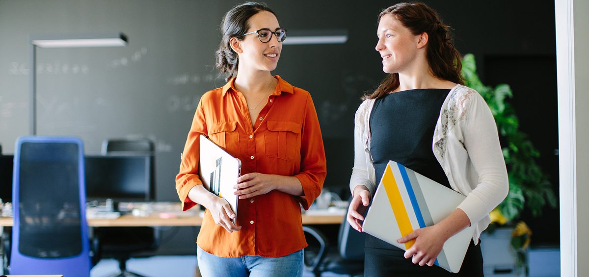 Two women walking in an office.